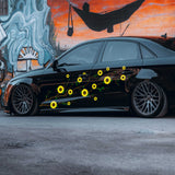 Black car with yellow sunflower decals in front of a mural