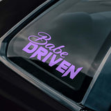Car window with 'Babe Driven' decal and a logo in the corner.