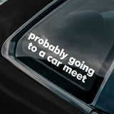 Car window with a decal reading 'probably going to a car meet' on a dark background