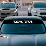 Car with a floral decal on the windshield in a parking lot.