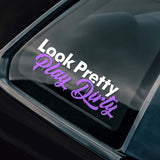 Car window with a decal reading 'Look Pretty, Play Dirty' on a black car.