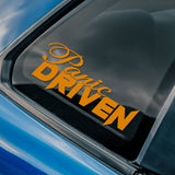 Car window with 'Panic Driven' decal and a logo in the corner.