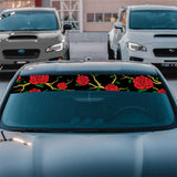 Car with a decorative rose pattern on the front window in a parking lot.