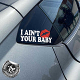 Car side mirror with 'I Ain't Your Baby' decal and visible brand logo.
