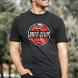 A person wearing a black t-shirt with a red and white retro car logo and the text 'Auto Club BAD' on the front.
