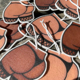 A collection of brown and white, double-sided air fresheners with the design of a human buttock and thighs wearing fishnet stockings.