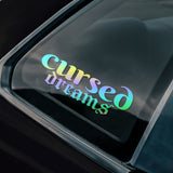 Holographic 'cursed dreams' gothic style sticker on a black car window.