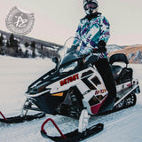 Person on a snowmobile in a snowy landscape with a visible brand logo.