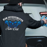 Person cleaning a car wearing a hoodie with a Bad Investments Auto graphic design on the back.