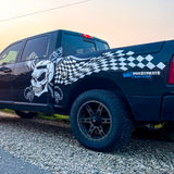 Black truck with skull and checkered design on a gravel surface