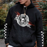 Person wearing a black hoodie with a logo and text, standing outdoors.