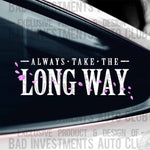 White and Pink vinyl decal mockup saying "Always Take The Long Way" with floating flower petals around the letters shown on a car window