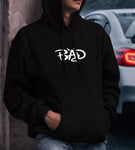 Male model wearing a black hooded sweater with “BAD” lettering design on it