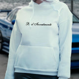 Female model wearing a white hooded sweater with “Bad Investments” cursive lettering design on it